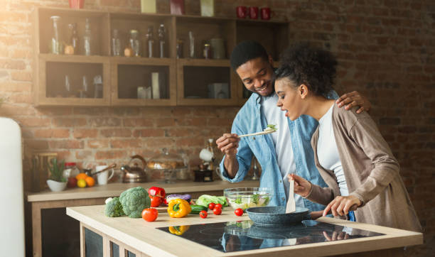 istock Happy african-american couple preparing dinner 1069988860