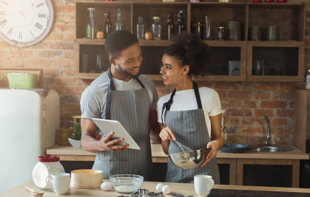 feliz pareja afroamericana de la hornada y el uso de la tableta - tart dessert tray bakery fotografías e imágenes de stock