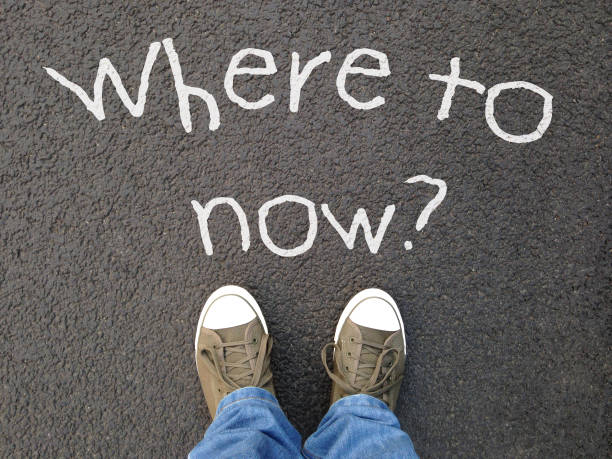 istock feet standing on road with where to now question written on asphalt 1069992354