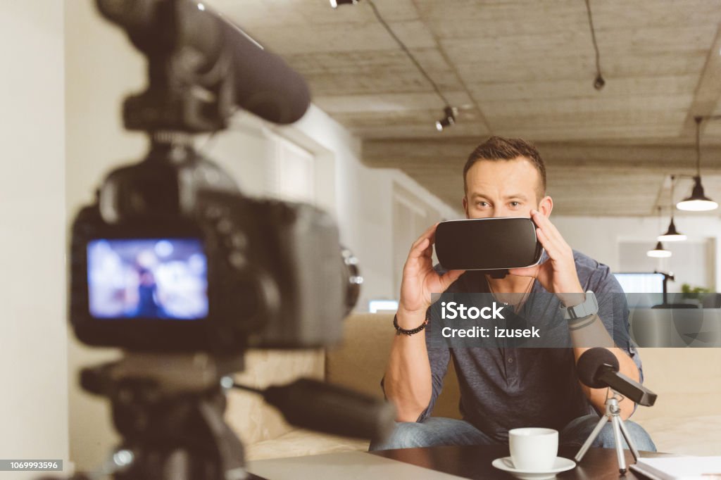 Vlogger making video on vr goggles Vlogger reviewing virtual reality glasses. Man using VR virtual reality goggles for a podcast. Discussion Stock Photo