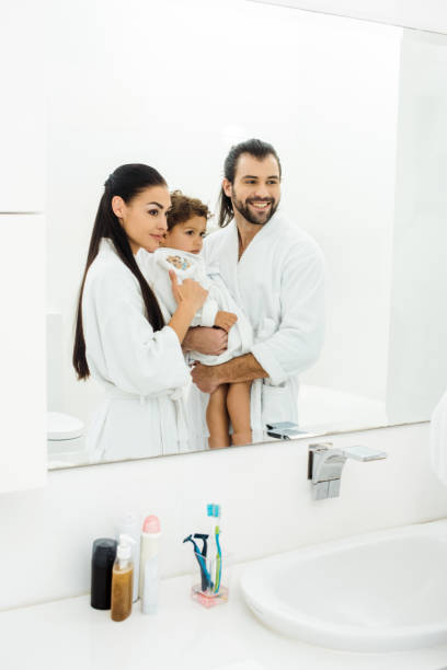 istock Family looking in mirror and smiling in white bathroom 1070000700