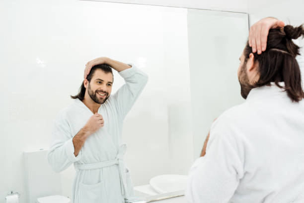 istock Handsome man looking in mirror and smiling in white bathroom 1070000862
