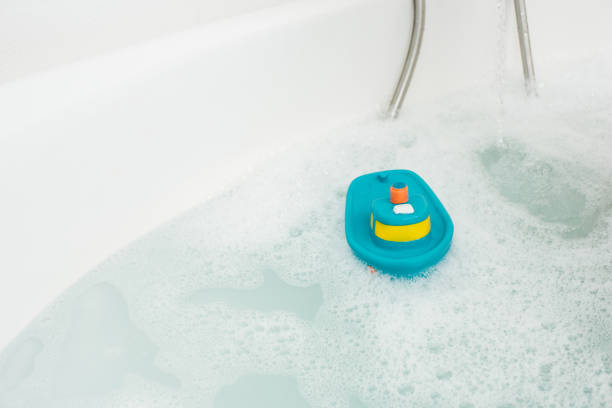 white bathtub with water and bath toy - bath toy imagens e fotografias de stock