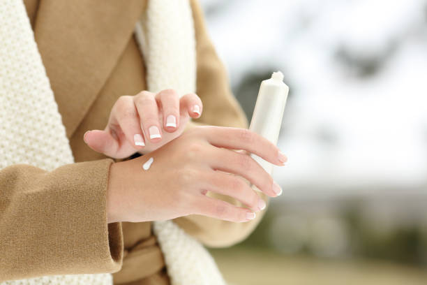 ผู้หญิงมือชุ่มชื้นครีมทาผิวในฤดูหนาว - female hand with tube of the body cream ภาพสต็อก ภาพถ่ายและรูปภาพปลอดค่าลิขสิทธิ์