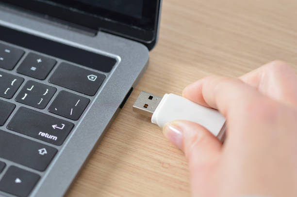 working with my laptop Close up of a woman hand connecting a pendrive in a laptop on a desktop usb stick photos stock pictures, royalty-free photos & images