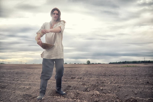 A young peasant of the Scandinavian appearance sows the field with grain