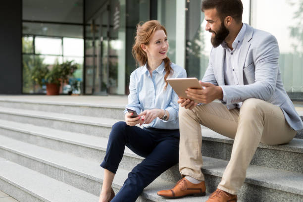 istock Two smiling young business people working on tablet outdoors 1070010294