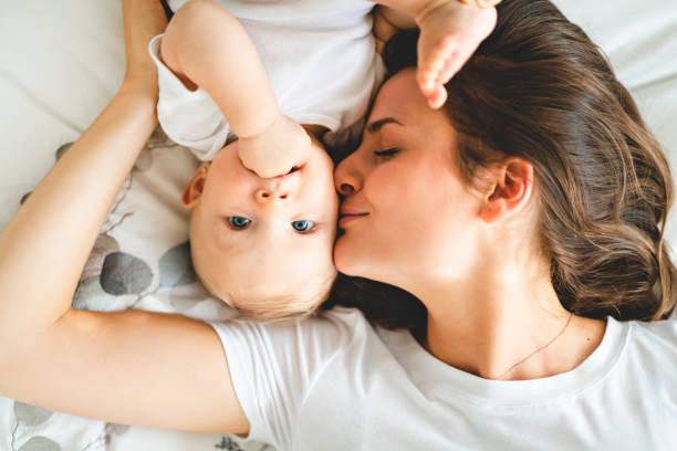 mère avec bébé sur lit passer bon moment - baby kissing mother lifestyles photos et images de collection