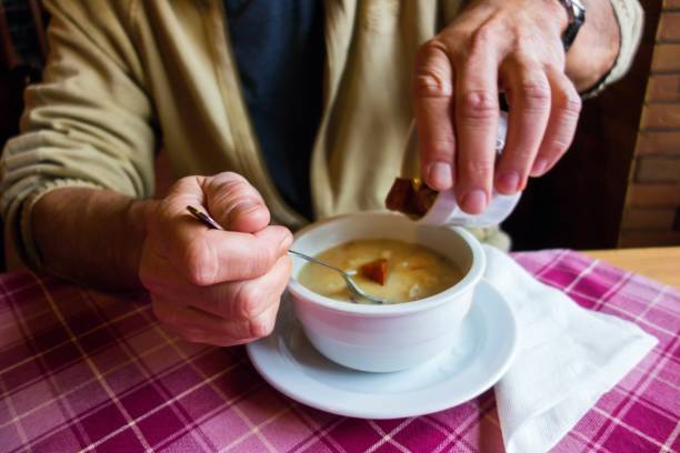 istock Man sprinkled bread into soup bowl. 1070027542