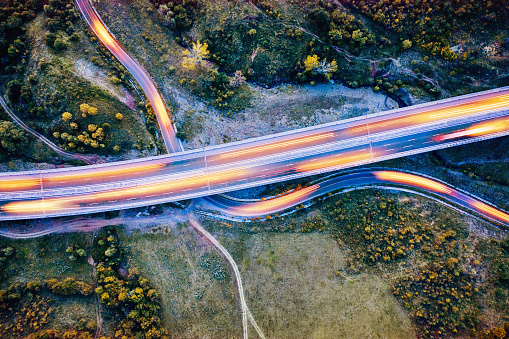Aerial view of a highway and a curving country road with light trails