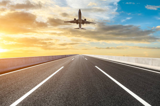 istock Asphalt road and sky flying airplane at sunset 1070031030