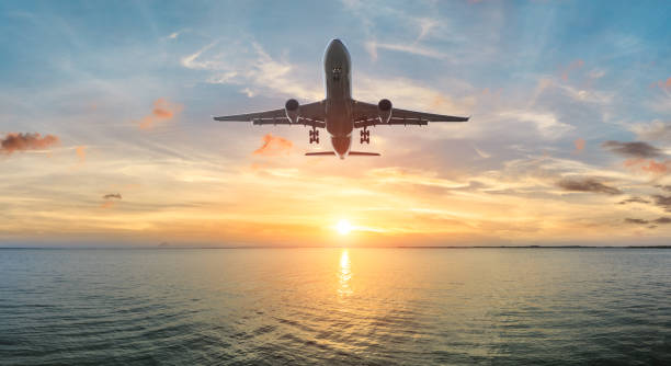 istock Airplane flying over the sea at sunset 1070032892