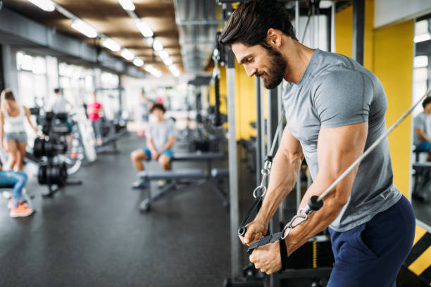 mec musclé bodybuilder faire des exercices dans la salle de gym - gym muscular build weights two people photos et images de collection