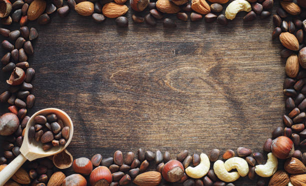 istock Different nuts on a wooden table. Cedar, cashew, hazelnut, walnuts and a spoon on the table. Many nuts are inshell and chistchenyh on a wooden background. 1070034892