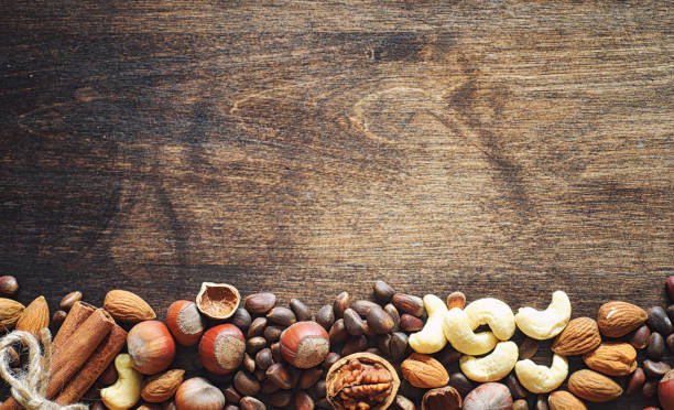 istock Different nuts on a wooden table. Cedar, cashew, hazelnut, walnuts and a spoon on the table. Many nuts are inshell and chistchenyh on a wooden background. 1070034992