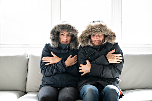 A couple have cold on the sofa at home with winter coat