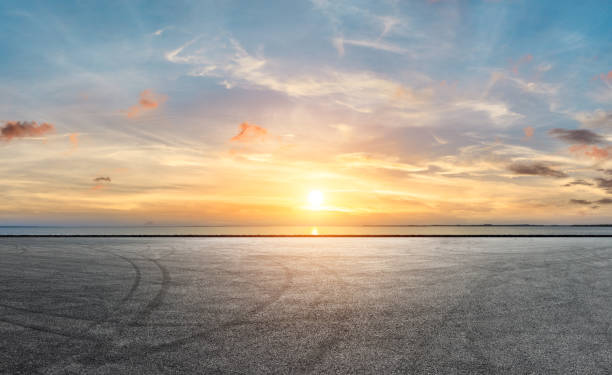 pavimentazione stradale in asfalto e cielo drammatico con costa - imbrunire foto e immagini stock