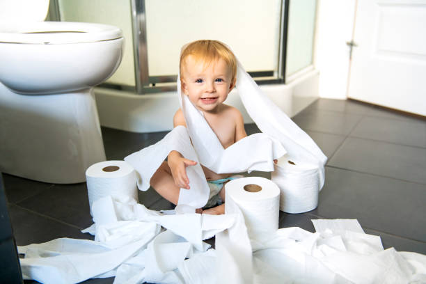 niño rasga encima de papel higiénico en el baño - travesura fotografías e imágenes de stock