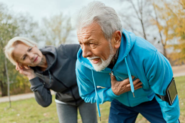 senior man suffering heart attack whilst jogging - chest pain imagens e fotografias de stock