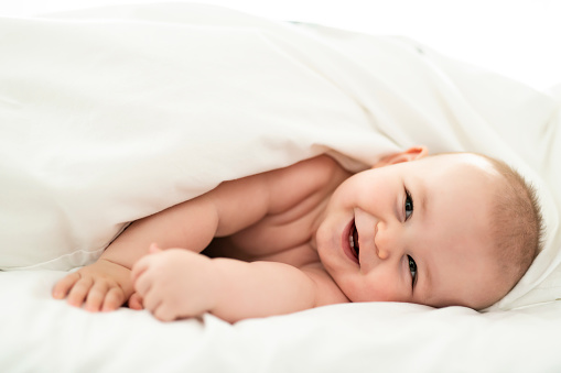 A happy baby lying on white sheet