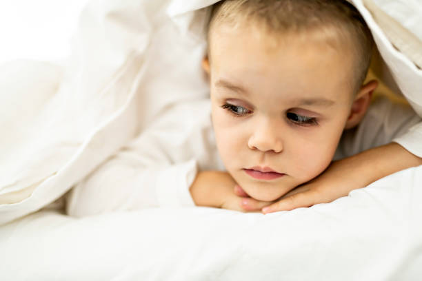 istock cute four years boy in white bedding 1070045442