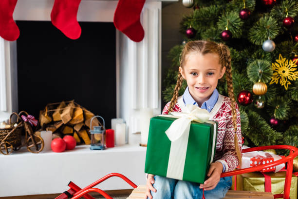 istock cute smiling child sitting on sled and holding christmas present 1070047752