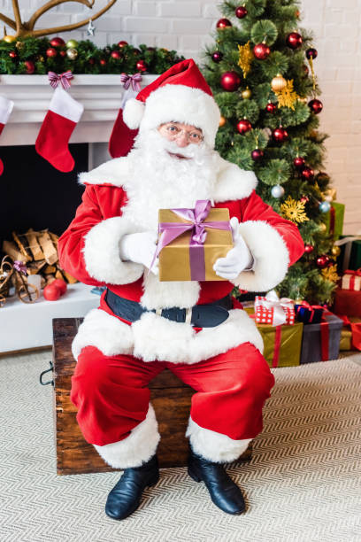 istock happy santa claus holding christmas present and looking at camera 1070052464