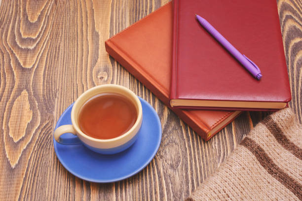 istock Blue tea cup with notebooks, a pen and a scarf on wooden table. 1070052758