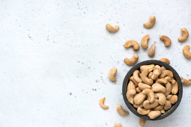 Cashew nuts in bowl on grey concrete background Cashew nuts in bowl on grey concrete background with copy space for text. Top view, healthy vegetarian food cashew photos stock pictures, royalty-free photos & images