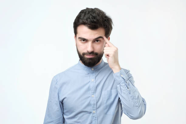 Let me think. Serious hispanic man with beard, keeps index finger on temple, recollect something in mind