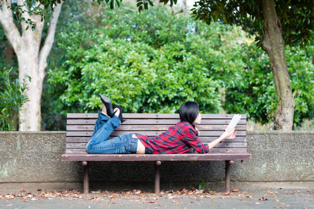 istock Woman reading a book on a park bench 1070058588