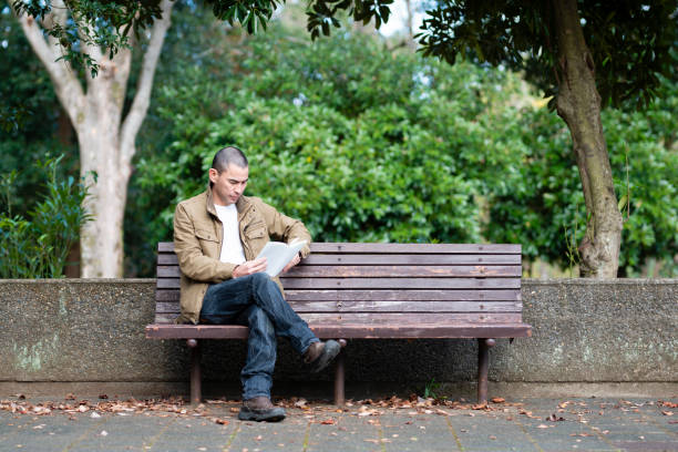 istock Man reading a book in a park bench 1070058884