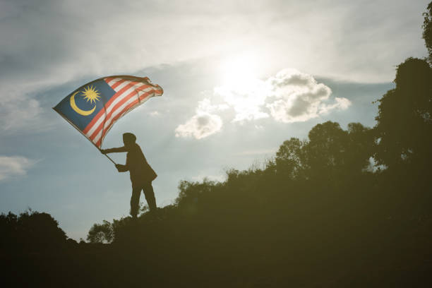 istock Silhouette Boy Waving Malaysian Flag Against Sky During Sunset 1070059064