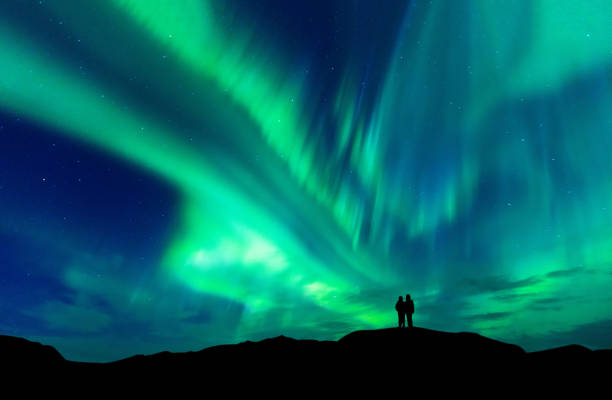 aurora borealis mit silhouette liebe romantisch zu zweit auf dem berg. flitterwochen reisekonzept - kontur fotos stock-fotos und bilder
