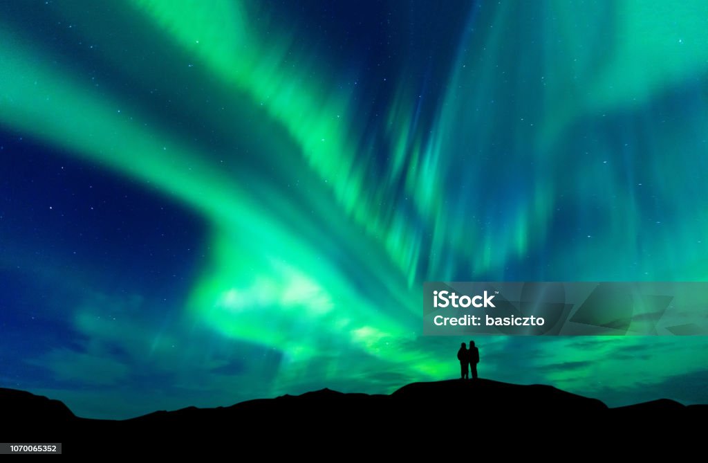 Aurora borealis with silhouette love romantic couple on the mountain.Honeymoon travel concept Aurora Borealis Stock Photo