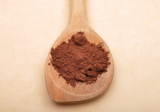istock Cacao powder on wooden spoon on brown background 1070067836