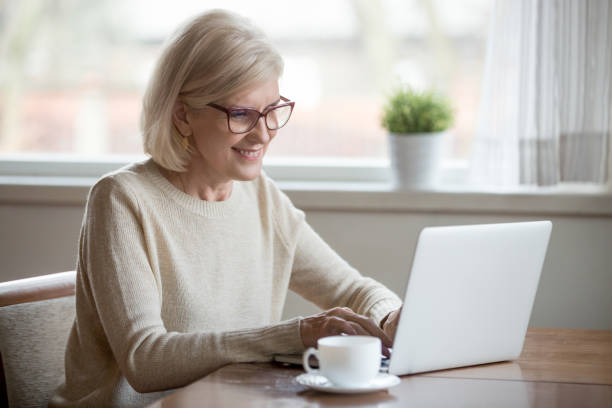 istock Happy aged woman busy using laptop at home 1070069240