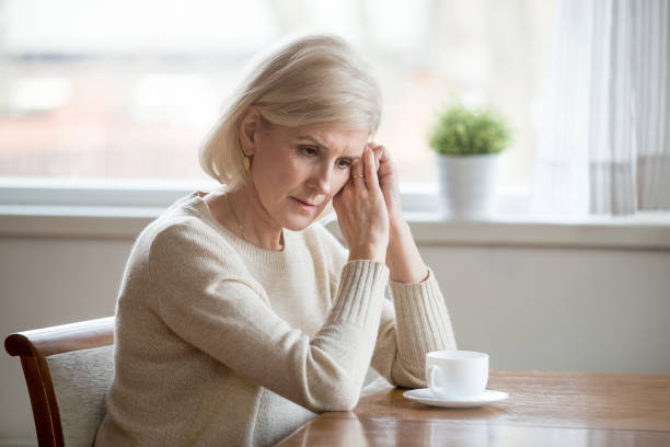 istock Concerned aged woman sit at table lost in thoughts 1070069290