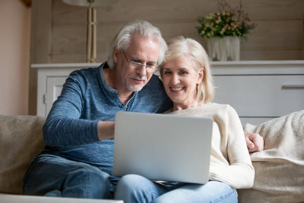 istock Happy aged couple relax on couch using laptop together 1070069370