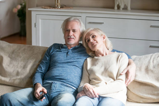 istock Happy aged couple relaxing on sofa watching TV 1070069430