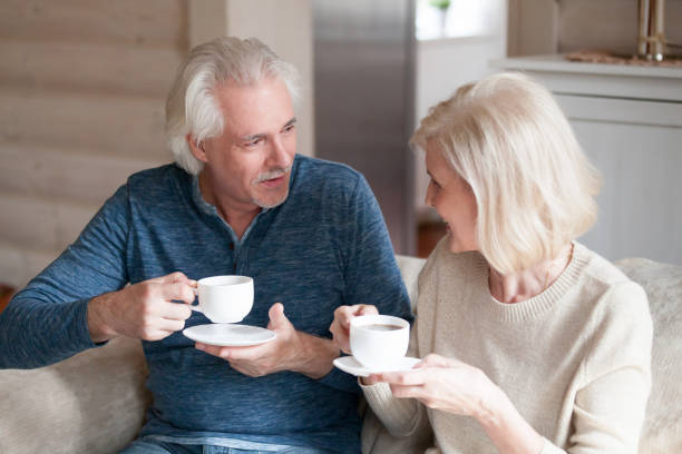 istock Happy senior couple drinking tea on couch talking 1070069502