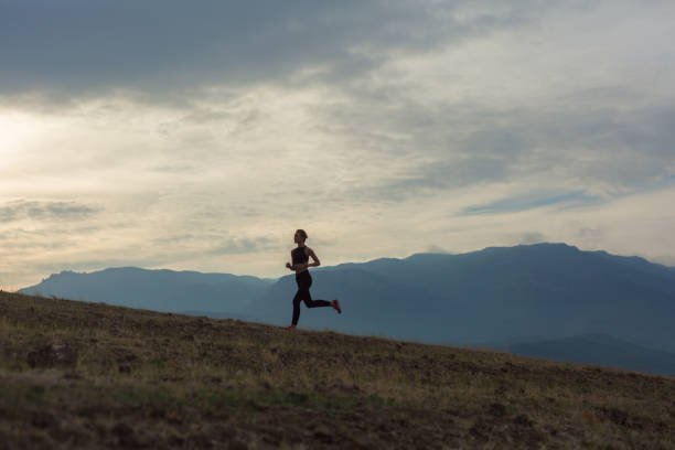 silhouette de fille mince est jogging dans les monts brumeux - distance running jogging running fog photos et images de collection