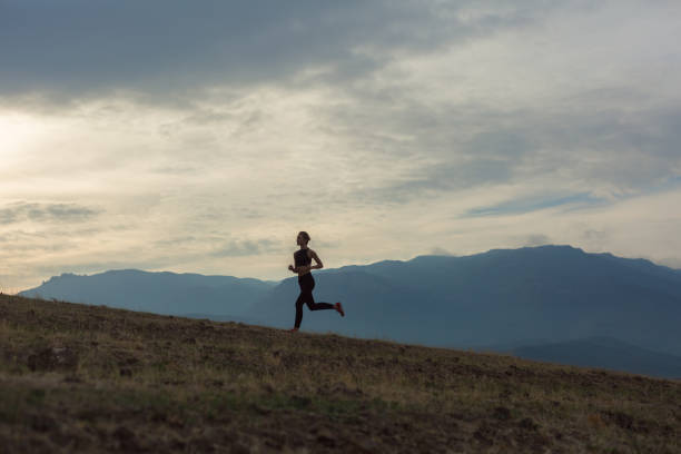 silhouette of slim girl is jogging in foggy mountains - colina acima imagens e fotografias de stock