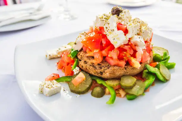 Dakos, Cretan salad with fresh vegetables, feta cheese and olives, Greece traditional cuisine.