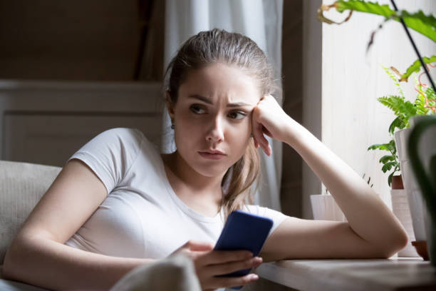 istock Sad frustrated female holding smartphone sitting on couch 1070079282