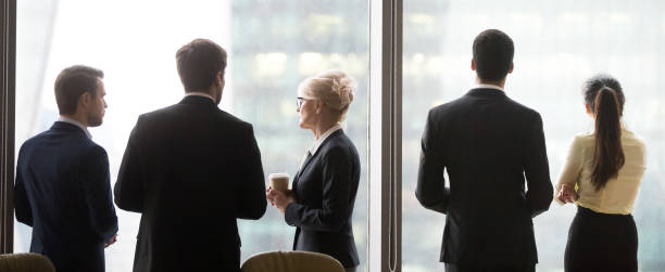 istock Back view of colleagues standing near window enjoying coffee break 1070079952