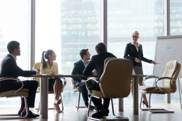 istock Smiling mature female coach making flipchart presentation to workers 1070080068