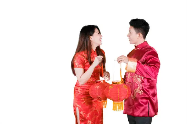 Picture of happy Asian couple carrying red lantern at Chinese new year in the studio, isolated on white background