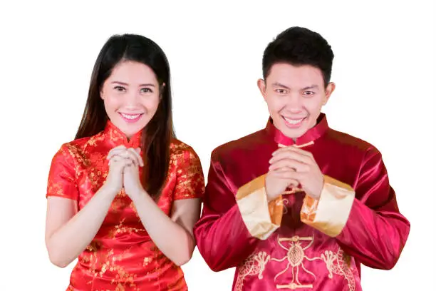 Picture of happy Chinese couple wearing cheongsam dress while congratulating Chinese new year in the studio