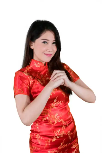Portrait of a pretty girl wearing traditional Chinese dress while giving gong xi fa chai greetings in the studio